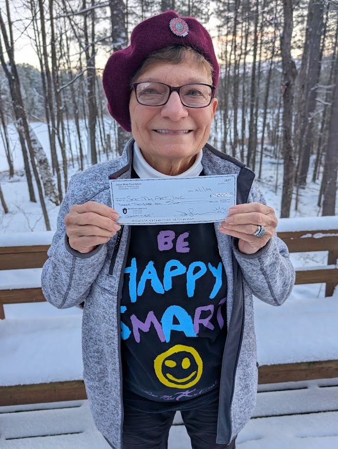 woman holding a Gratitude Grant contribution check from the Jason Mraz Foundation.